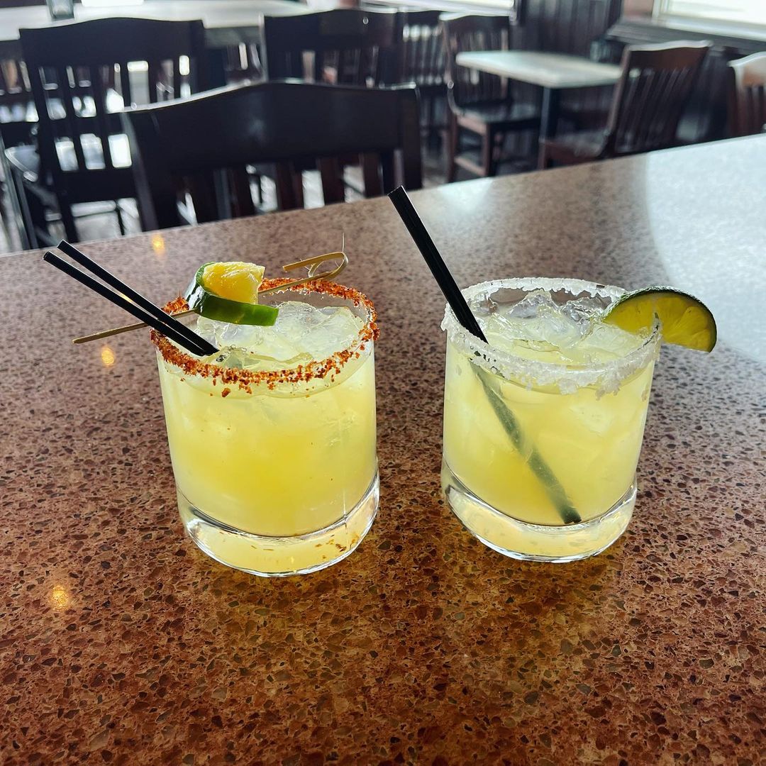 Two margaritas sitting on a counter.