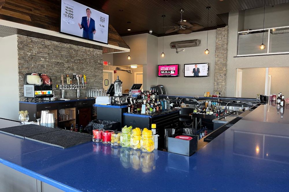 A bar with televisions and a blue counter.